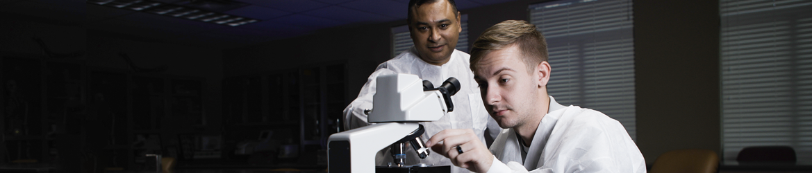 Professor Bakht teaches a student while using the microscope.
