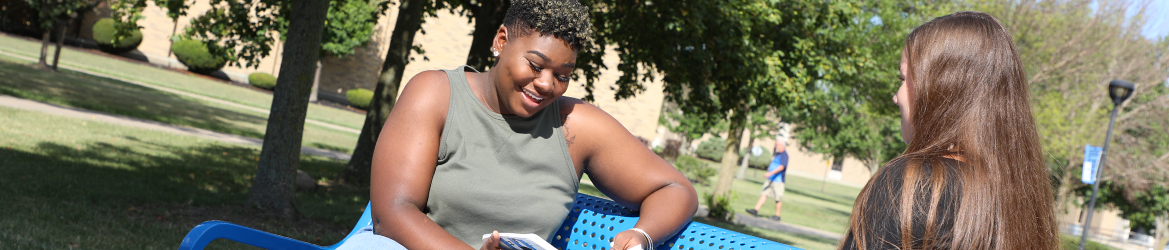 Female students chatting outside at Hilbert College campus. 