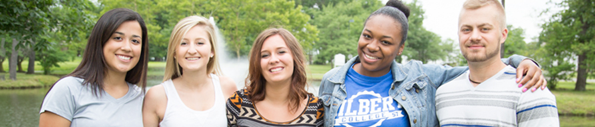 Students posing for the camera in front of the fountain at Hilbert Campus.