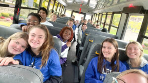 Hilbert students posing for pictures on a bus.