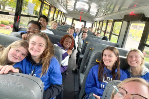 Hilbert students posing for pictures on a bus.