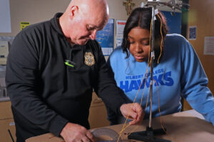 A Hilbert student learns from a professor on blood splatter techniques.