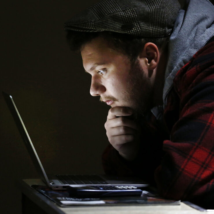 A Hilbert college student studying a laptop screen intently.