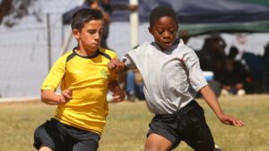 Kids playing soccer during the summer.