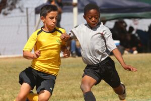 Kids playing soccer during the summer.